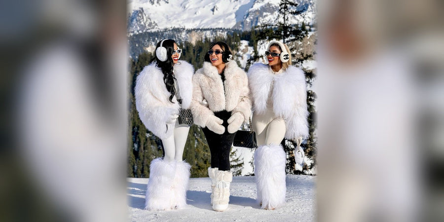 Three women in white fur jackets and fur snow boots on a snowy mountain