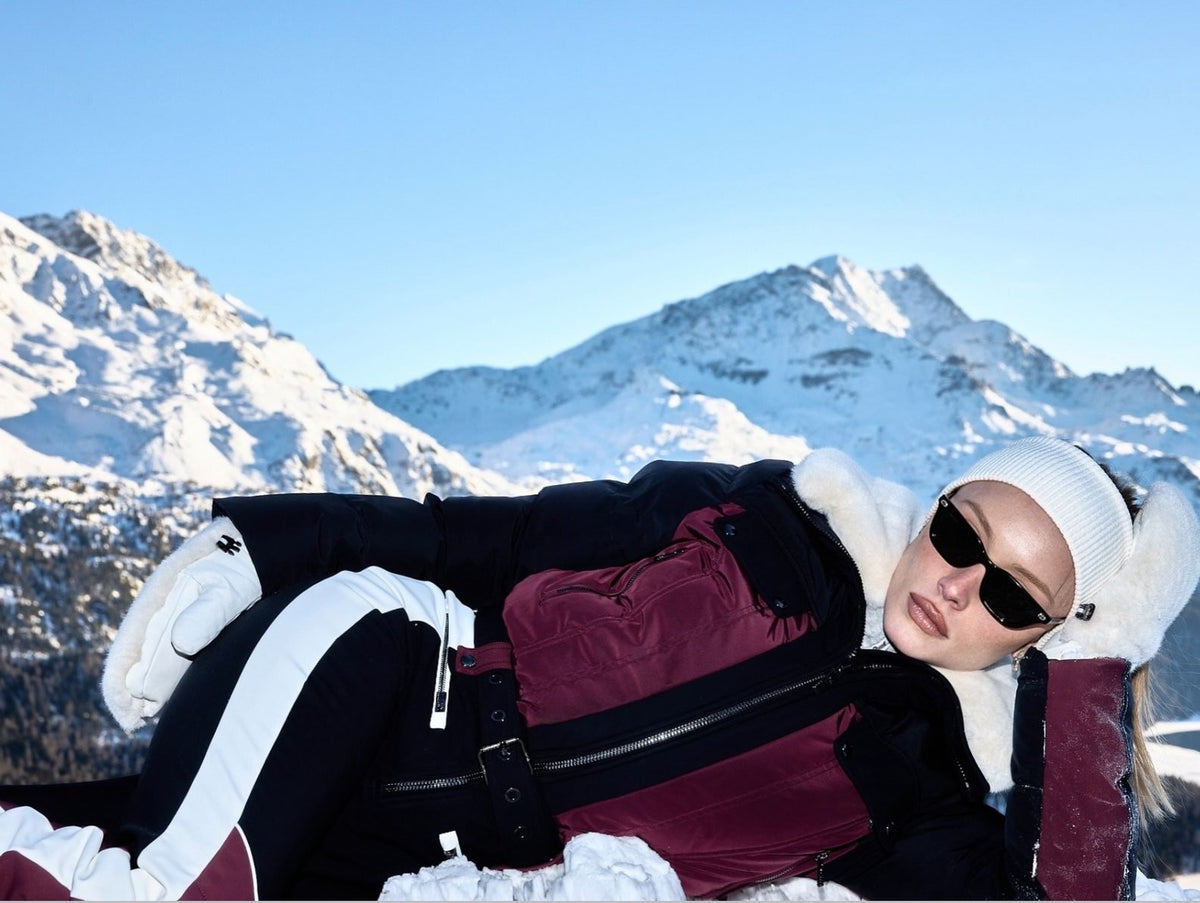 Woman in a Moncler ski suit against snow-capped alpine peaks